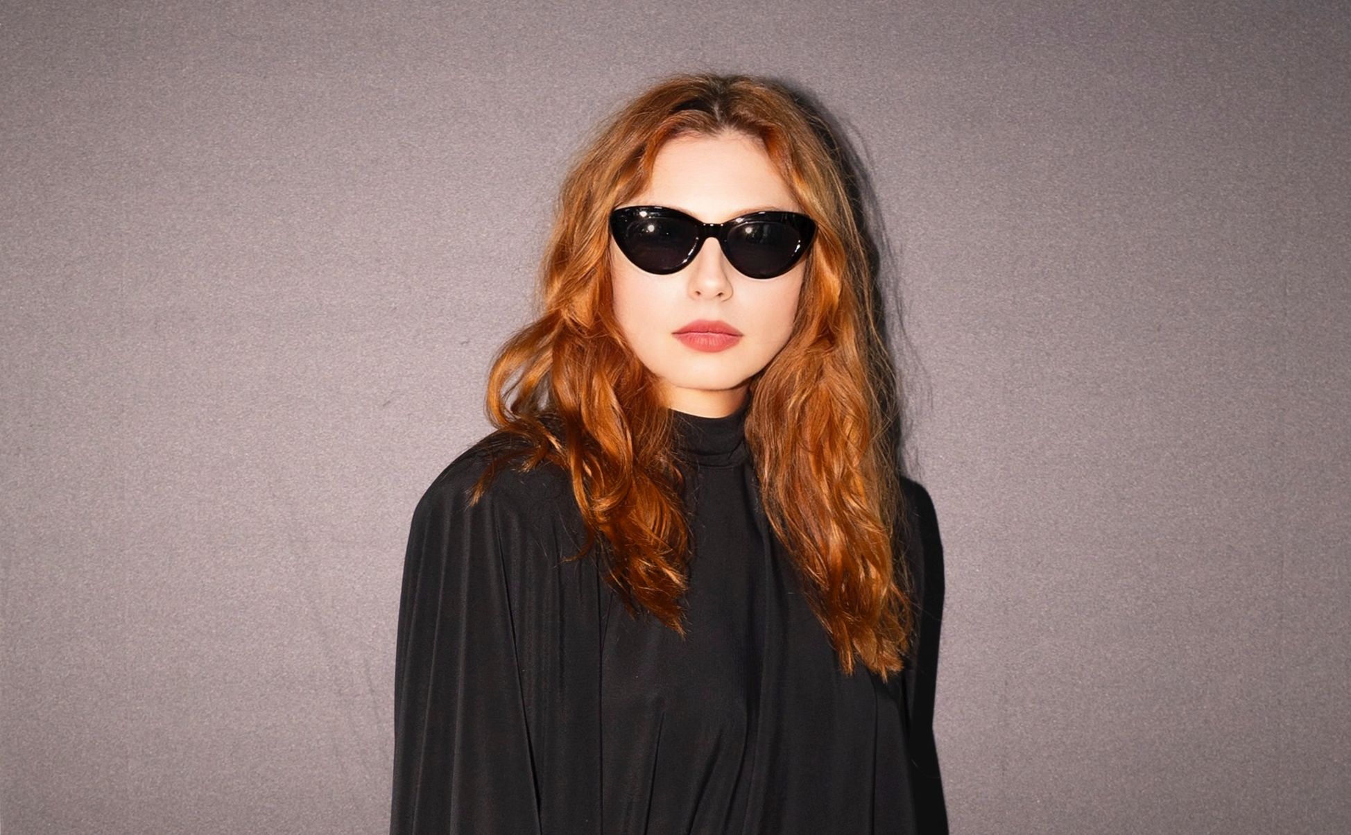 Poznata glumica odabrala je kreaciju s potpisom domaćeg brenda eNVy room, i to u klasičnoj crnoj nijansi koja je uvijek sinonim za eleganciju. Duga silueta haljine u potpunosti prati liniju tijela, ali na vrlo suptilan način – bez pretjeranog naglašavanja, već s dozom profinjene ležernosti. Puhasti, blago voluminozni rukavi donose dodatnu notu retro šarma, dok visoki struk s fokusom na detalj u vidu crvene satenske vrpce i ukrasne broševe unosi neočekivanu dozu glamura i boje. Najveći adut cijelog stylinga je upravo balans: dramatična crna haljina, kontrastni crveni akcent i odvažan izbor modnih dodataka u vidu crvenih cipela koji upotpunjuju vizualnu priču. Look je zaokružen diskretnim, ali upečatljivim makeupom te raskošnom kosom stiliziranom u mekanim valovima. Tamne naočale dale su cijeloj kombinaciji dojam hollywoodskog glamura i misterije. Judita je ovim pojavljivanjem pokazala da se ne boji modnih eksperimenata, ali uvijek bira rješenja koja naglašavaju njezinu osobnost i sofisticiranost. Ovaj outfit savršeno dokazuje da prava modna snaga leži u detalju – a Judita ga je pretvorila u svoj zaštitni znak večeri. Naš je zaključak jasan: Judita Franković Brdar i eNVy room stvorili su jedno od onih izdanja koje se pamti. Glumica se u ovom upečatljivom looku pojavila upravo na reviji modnog brenda eNVy room.