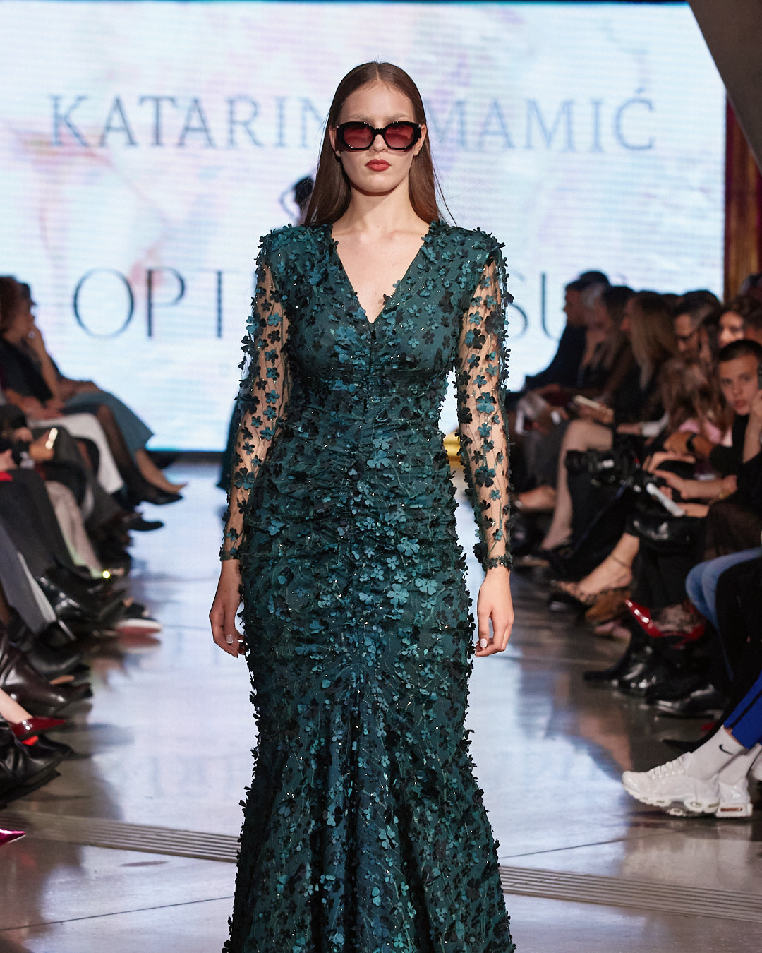 Katarina Mamić, moda, hrvatski dizajner, modna revija, večer mode, modni dizajn, kolekcija inspirirana Istanbulom, orijentalni luksuz, luksuzna moda, modni događaj, hrvatska moda, modna scena, suvremeni luksuz, ženska moda, elegantna kolekcija, indigo plava, sedefasta boja, zelena nijansa, zlatni detalji, modni trendovi, high fashion, modna estetika, hrvatski brend, fashion event, hrvatski dizajneri, modni show, fashion week, couture, ready to wear, modna inspiracija, orijentalni glamur, glamurozni modeli, modna pista, sofisticirana moda, ekskluzivna kolekcija, dizajnerska moda, modna senzacija, modna priča, Visus optika, sunčane naočale, modni dodaci, luksuzni detalji, suvremena elegancija, moderni luksuz, modna vizija, modni izričaj, ženstvena moda, elegantni krojevi, profinjeni stil, hrvatski dizajn, modna kolekcija, inspiracija Istanbulom, luksuzni materijali, fashion lovers, modna sofisticiranost, modna umjetnost, elegantna žena, glamur, fashion inspiration, fashion show, fashion collection, luxury fashion, contemporary fashion, fashion designer, stylish look, statement pieces, elegant dresses, oriental style, modern elegance, chic style, fashion editorial, trend report, street style, high-end fashion, fashion photography, red carpet look, luxury lifestyle, fashion aesthetic, design inspiration, handmade fashion, timeless elegance, exclusive look, women empowerment, fashion moment, elegant silhouettes, fashionista, style icon, fashion news, fashion trends, designer collection, Croatian fashion, Istanbul inspiration, elegant luxury, luxe fashion, urban chic, fashion statement, modern woman, Croatian designer, fashion fusion, stylish details, contemporary design, fashion magazine, fashion week Croatia.