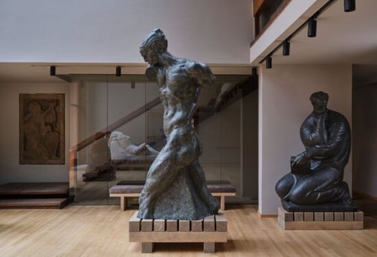 Obnovljeni Atelijer Meštrović novim postavom otvara vrata sredinom prosinca Otvaranje zagrebačkog Atelijera Meštrović nakon tisuću dana Nakon dugotrajne obnove uzrokovane potresima, zagrebački Atelijer Meštrović ponovno se otvara sredinom prosinca s novim stalnim postavom. Projekt je vodila ravnateljica Muzeja Ivana Meštrovića Sandra Grčić Budimir, postav potpisuje muzejska savjetnica Barbara Vujanović, arhitektonsko i likovno oblikovanje Damir Gamulin, Antun Sevšek i Jasmin Ćemanović iz Organiziranog oblikovanja. Osvježeni prostor iznova naglašava vrijednost ove jedinstvene lokacije, gdje se prožimaju Meštrovićev obiteljski i stvaralački život. Kuća s vrtom i odvojenim, ali duboko povezanim atelijerom čuva atmosferu u kojoj je živio sa suprugom Olgom i četvero djece te stvarao djela u različitim materijalima, danas raspoređena u pregledne tematske cjeline. Kompleks u Mletačkoj 8 i 10, koji je Meštrović 1920-ih preoblikovao u skladnu cjelinu, ostao je spomen na razdoblje intenzivnog rada i živog intelektualnog života. Danas je to prepoznatljiva memorijalna adresa na kojoj je nastao niz njegovih ključnih djela. Muzeji Ivana Meštrovića nastavljaju brinuti o baštini koju je umjetnik ostavio Darovnicom iz 1952. godine: Atelijeru u Zagrebu, Galeriji Meštrović i Crikvinama–Kaštilcu u Splitu te Crkvi Presvetog Otkupitelja u Otavicama. Sva su ta mjesta obilježena njegovim arhitektonskim i kiparskim stvaralaštvom, a novi zagrebački postav donosi suvremeni, promišljeni pristup interpretaciji njegova života i djela. U šezdeset godina postojanja muzeja, ovo je prvo potpuno novo oblikovanje stalnog postava. Cilj je jasnije predstaviti opus iz fundusa i pohrane Atelijera, uz birane skulpture iz fundusa Galerije Meštrović. Uz antologijska djela poput Miloša Obilića, Povijesti Hrvata i ženskih aktova međuratnoga razdoblja, izdvaja se i posebno vrijedan raritet — portret kralja Faisala, vođe koji se za arapsku neovisnost borio uz Lawrencea od Arabije. Riječ je o rijetko izlaganom djelu koje svjedoči o međunarodnom ugledu koji je Meštrović uživao i o razgranatoj mreži njegovih svjetskih kontakata. Ključan dio novog postava čine tekstovi Barbare Vujanović i Mate Marića, koji nude inovativan način interpretacije Meštrovićeve biografije i stvaralaštva. Svježe napisani, lako prohodni tekstovi stvaraju novi značenjski i emotivni okvir, vode posjetitelja kroz različite slojeve umjetnikova života, te olakšavaju dublje razumijevanje njegova opusa u suvremenom kontekstu. Dinamičnost postava podržana je fleksibilnim postamentima koji omogućuju rotacije skulptura i cikličke edukativne sadržaje. Time se potiče stalno preispitivanje i novo čitanje Meštrovićeva rada, a sve zajedno predstavlja iskorak prema suvremenoj muzeološkoj praksi. Atelijer Meštrović od 14. prosinca bit će otvoren za javnost, a ulaz je do kraja godine besplatan — simboličan povratak Meštrovićeva doma u život nakon tisuću dana zatvorenosti i odsutnosti publike.