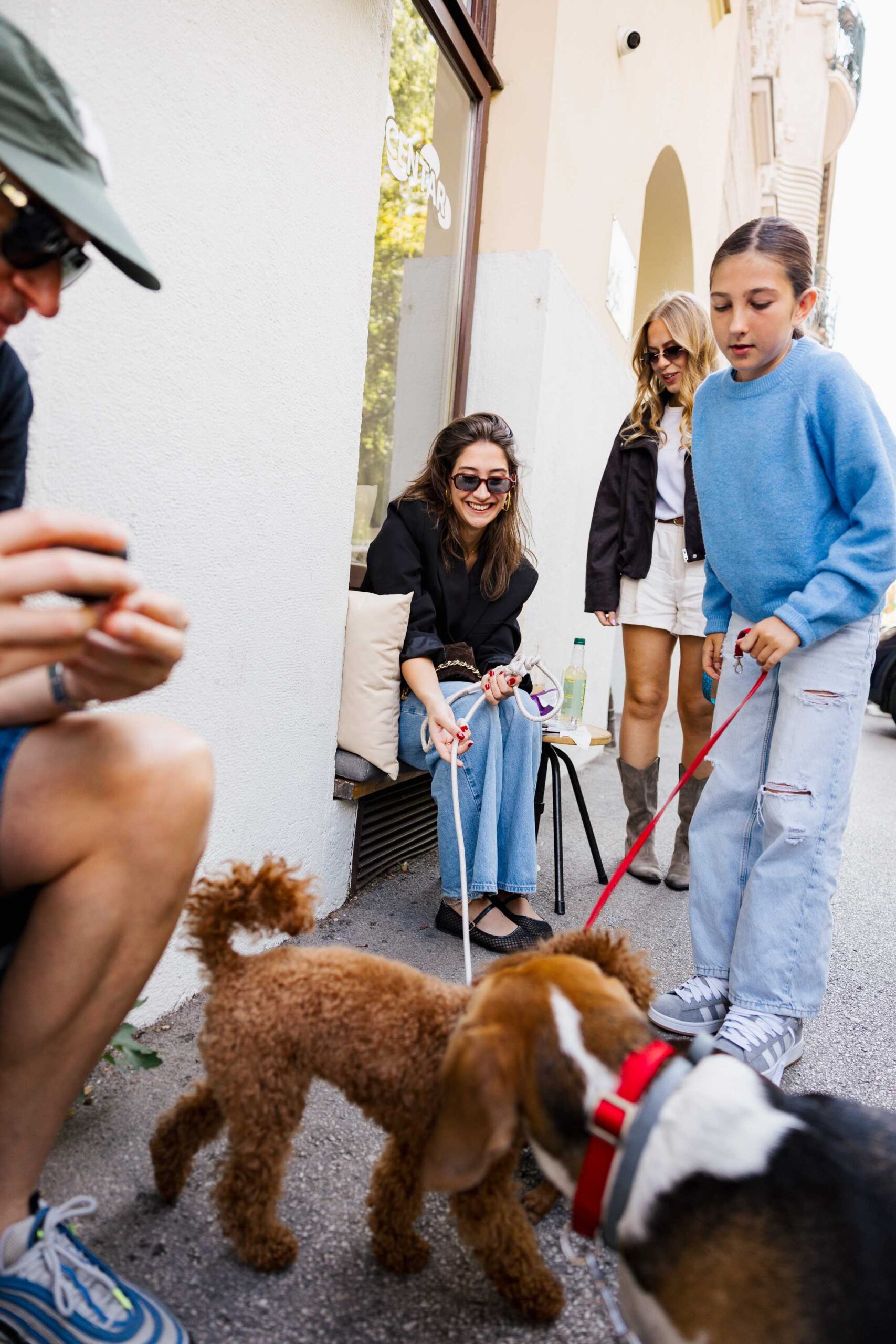 Treće izdanje Dogs’ Caféa Zagreb održano je u Botaničaru, gdje su se ponovno okupili brojni vlasnici pasa zajedno sa svojim četveronožnim pratiteljima. Nakon dva prethodna zagrebačka izdanja i prvog druženja održanog u Splitu, projekt se vratio u Zagreb s programom koji je zadržao osnovnu ideju koncepta, stvaranje mjesta na kojem su psi dobrodošli i na kojem njihovi vlasnici mogu provesti vrijeme s njima bez uobičajenih ograničenja koja često prate boravak s ljubimcima u gradskim prostorima. Dogs’ Café od prvog izdanja zamišljen je kao pop-up događanje koje se gradi oko svakodnevnog života ljudi sa psima. Umjesto klasičnog događanja na kojem vlasnici dolaze bez svojih ljubimaca, ovdje upravo psi određuju karakter susreta. Oni dolaze zajedno sa svojim ljudima, upoznaju druge pse, istražuju prostor i spontano stvaraju situacije u kojima se upoznaju i njihovi vlasnici. Treće zagrebačko izdanje nastavilo je upravo takav format, a Botaničar je za jedan dan postao mjesto susreta ljudi koje povezuje isto iskustvo života sa psima. Razvoj projekta vidljiv je i kroz publiku koja se okuplja na svakom novom izdanju. Dio posjetitelja vraća se nakon prethodnih druženja, dok se istodobno pridružuju novi vlasnici pasa koji Dogs’ Café posjećuju prvi put. Takav spoj stalnih i novih posjetitelja postupno je stvorio zajednicu koja se više ne okuplja samo zbog pojedinačnog programa, nego i zbog mogućnosti upoznavanja drugih ljudi sa sličnim svakodnevnim iskustvima, pitanjima i interesima vezanima uz njihove ljubimce. Program u Botaničaru bio je prilagođen upravo takvom načinu druženja. Posjetitelji su tijekom dana mogli provoditi vrijeme sa svojim psima, upoznavati druge vlasnike i koristiti sadržaje pripremljene za ovu priliku, dok su četveronožne goste čekali puppuccino i prigodni pokloni. Ideja nije bila odvojiti program za vlasnike od programa za pse, nego omogućiti da većinu vremena provedu zajedno, što je od početka jedno od prepoznatljivih obilježja Dogs’ Caféa. Svoj prostor na događanju ponovno je imao Pet Centar, gdje su posjetitelji mogli upoznati nove proizvode namijenjene kućnim ljubimcima te pronaći praktična rješenja za svakodnevnu brigu o psima. Takav sadržaj uklopio se u koncept događanja koje uz druženje otvara prostor i za teme prehrane, njege, zdravlja i drugih pitanja s kojima se vlasnici susreću tijekom života sa svojim ljubimcima. Poseban dio trećeg zagrebačkog izdanja bila je izložba fotografija pasa autora Lukše Marottija, realizirana uz pokroviteljstvo Vetti Groupa. Fotografije su zabilježile pse u različitim situacijama i raspoloženjima, bez potrebe da ih se promatra samo kao pratnju njihovih vlasnika. Svaki fotografirani pas dobio je vlastiti kadar, izraz i karakter, pa je izložba unutar prostora Botaničara funkcionirala kao zasebna vizualna cjelina posvećena upravo životinjama oko kojih je cijeli događaj nastao. Programu se ponovno pridružio i Nik Titanik, koji je za posjetitelje izrađivao personalizirane karikature. Njegov kutak privukao je velik interes već tijekom proljetnog Dogs’ Caféa, kada zbog broja zainteresiranih dio posjetitelja nije stigao doći na red. Novo izdanje zato je donijelo još jednu priliku vlasnicima koji su željeli ponijeti kući osobnu uspomenu sa svojim psom. Karikature su nastajale tijekom samog događanja, pa su vlasnici iz Botaničara odlazili s radom napravljenim upravo za njih i njihove ljubimce. Uz zabavne i kreativne sadržaje, dio programa bio je posvećen zdravlju pasa i neposrednom razgovoru s veterinarima. U suradnji s Vetti Groupom posjetiteljima su na raspolaganju bili dr. Saša Dujanović i dr. Ana Ritoša, s kojima su mogli razgovarati o zdravstvenim pitanjima vezanima uz svoje ljubimce. Vlasnici su mogli zatražiti stručni savjet, razgovarati o konkretnim nedoumicama te iskoristiti mogućnost besplatnog veterinarskog pregleda. Na taj je način stručna veterinarska podrška bila dostupna u neformalnom okruženju u kojem su vlasnici već boravili zajedno sa svojim psima. Humanitarni dio ostao je sastavni dio Dogs’ Caféa i u njegovu trećem zagrebačkom izdanju. Projekt od početka koristi okupljanja i vidljivost događanja kako bi pažnju usmjerio i prema psima koji još nemaju svoj dom. Dosadašnja izdanja već su završila konkretnim udomljenjima, pa Dogs’ Café uz program za vlasnike i njihove ljubimce daje prostor i njuškama koje tek čekaju svoje ljude. Upravo se kroz tri zagrebačka izdanja može pratiti kako se prvotna ideja jednodnevnog okupljanja postupno pretvorila u događanje kojem se dio publike redovito vraća. Ljudi koji su se upoznali na ranijim izdanjima ponovno se susreću, novi posjetitelji ulaze u zajednicu, a psi ostaju prirodan razlog za početak razgovora. Razmjenjuju se iskustva o prehrani, zdravlju, ponašanju, svakodnevnim navikama i životu u gradu sa psom, ali velik dio druženja nastaje spontano, bez unaprijed zadanog programa. „Sretna sam zbog fantastičnog odaziva i sjajne atmosfere na trećem po redu zagrebačkom DOGS' CAFE-u. Veliki broj posjetitelja i njihovih četveronožnih ljubimaca potvrdili su važnost i potrebu ovakvih susreta za našu zajednicu. Veliko hvala Botaničaru koji je svojim divnim ambijentom omogućio da ovaj pop-up event dobije novo ruho. Gledati toliko sretnih pasa na jednom mjestu najveća je nagrada za sav trud oko organizacije. Nadamo se da će i ovog puta njuškice koje traže dom imati sreće i pronaći svoje ljude. Hvala vam što ste dio naše priče!“, izjavila je Petra Turkulin Odak, autorica koncepta Dogs’ Café. Treće izdanje u Botaničaru nastavilo je koncept bez udaljavanja od njegove početne ideje. Psi su tijekom cijelog događanja bili ravnopravni sudionici, a sadržaji su bili organizirani oko vremena koje vlasnici provode sa svojim ljubimcima. Fotografije Lukše Marottija, karikature Nika Titanika, veterinarski savjeti i pregledi, Pet Centar, puppuccino i prigodni pokloni bili su različiti dijelovi istog susreta. Dogs’ Café Zagreb tako je još jednom okupio ljude koji svoje pse ne ostavljaju kod kuće kada odlaze na druženje, nego ih vode sa sobom. U Botaničaru su upravo psi bili razlog dolaska, novih poznanstava, razgovora i zajedničkih fotografija, a za neke od njih ovakva okupljanja mogu značiti i nešto mnogo konkretnije, priliku da među posjetiteljima pronađu ljude s kojima će otići u svoj novi dom.